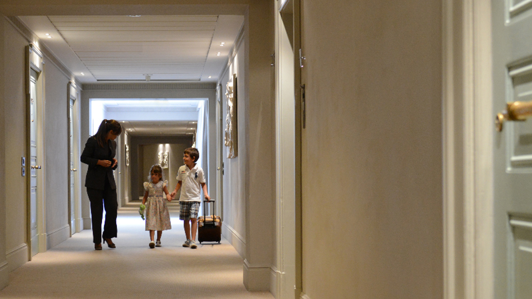 Two children and a member of staff in a hotel corridor.