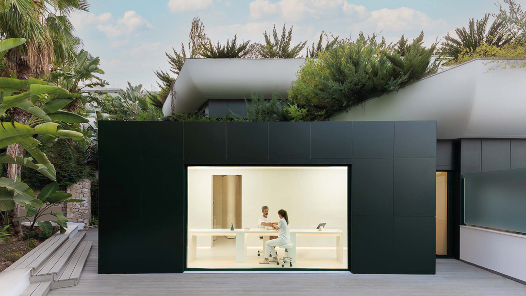 A modern building with two people seen through a large window at the SHA Alicante resort.