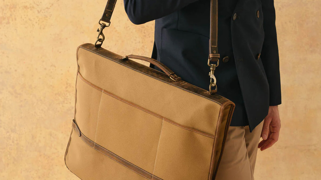 A man with a suit carrier bag from Tusting.