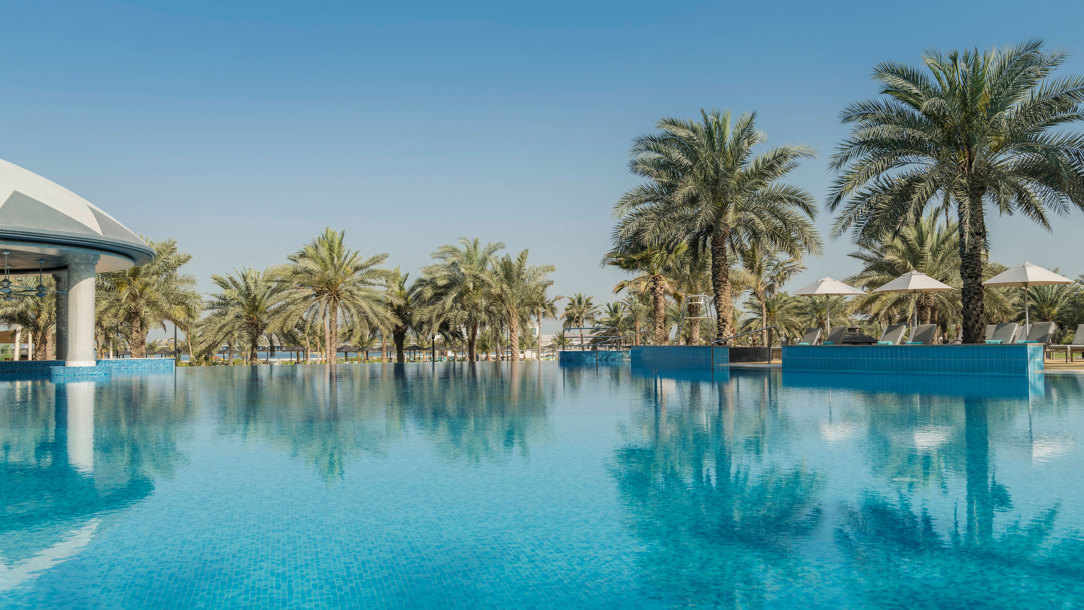 A swimming pool at a Dubai hotel with palm trees surrounding it.
