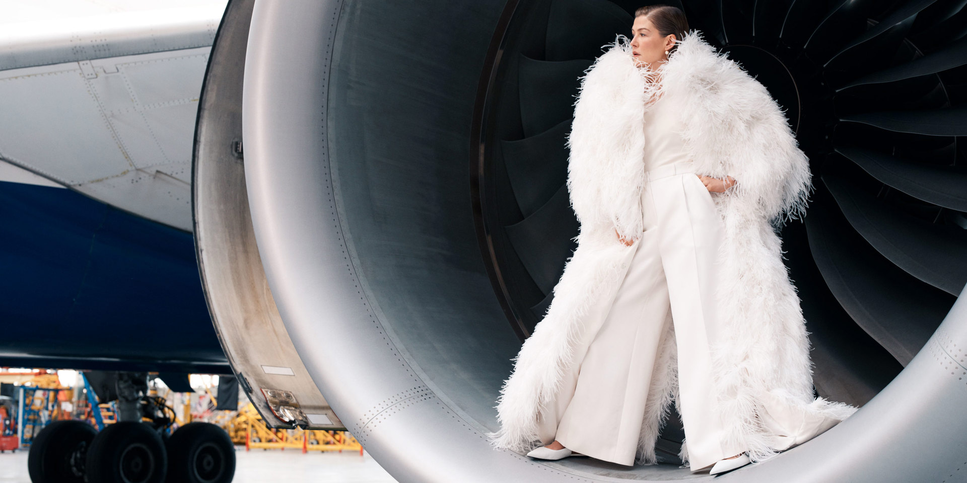 A portrait of Rosamund Pike standing in the engine of a British Airways plane.