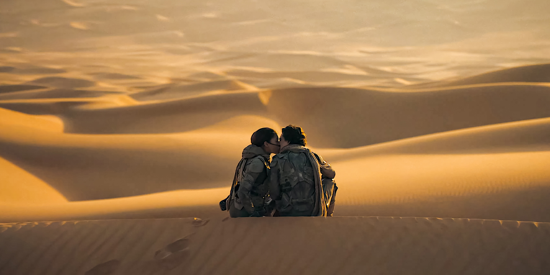 A still from the second 'Dune' film with a couple sitting in the desert.