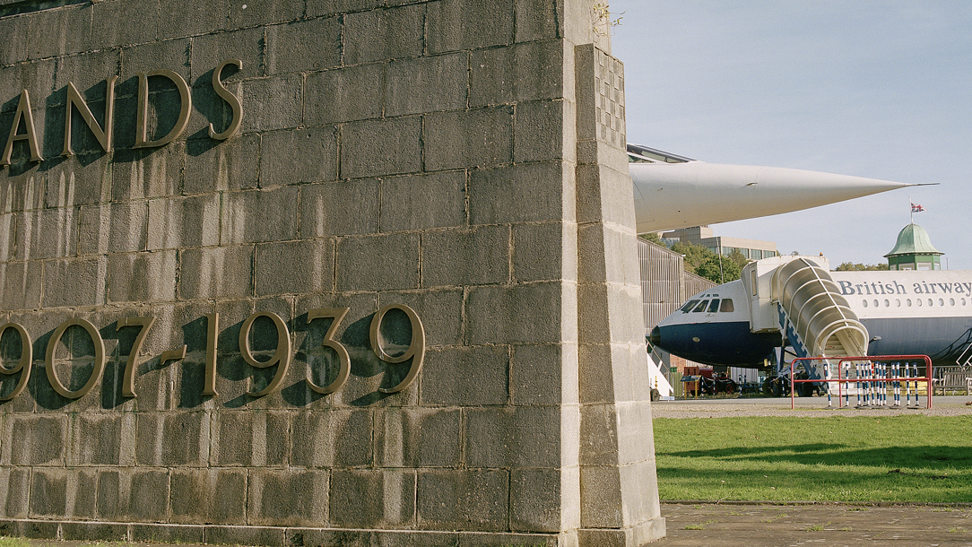 The nose of a Concorde airplane behind a sign for Brooklands museum.