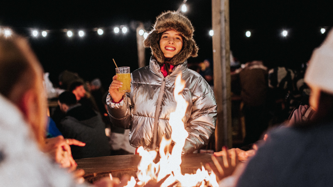 A woman enjoying an open fire at  La Folie Douce Hotels Chamonix.