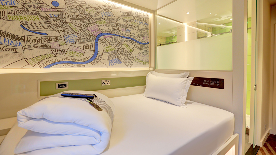 A hotel room with a map as artwork next to the bed.