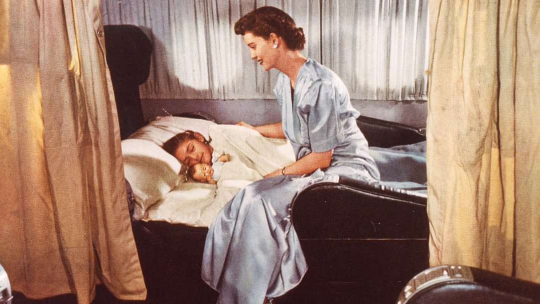 A woman tucking a child in bed onboard at BOAC Boeing Statocruiser.