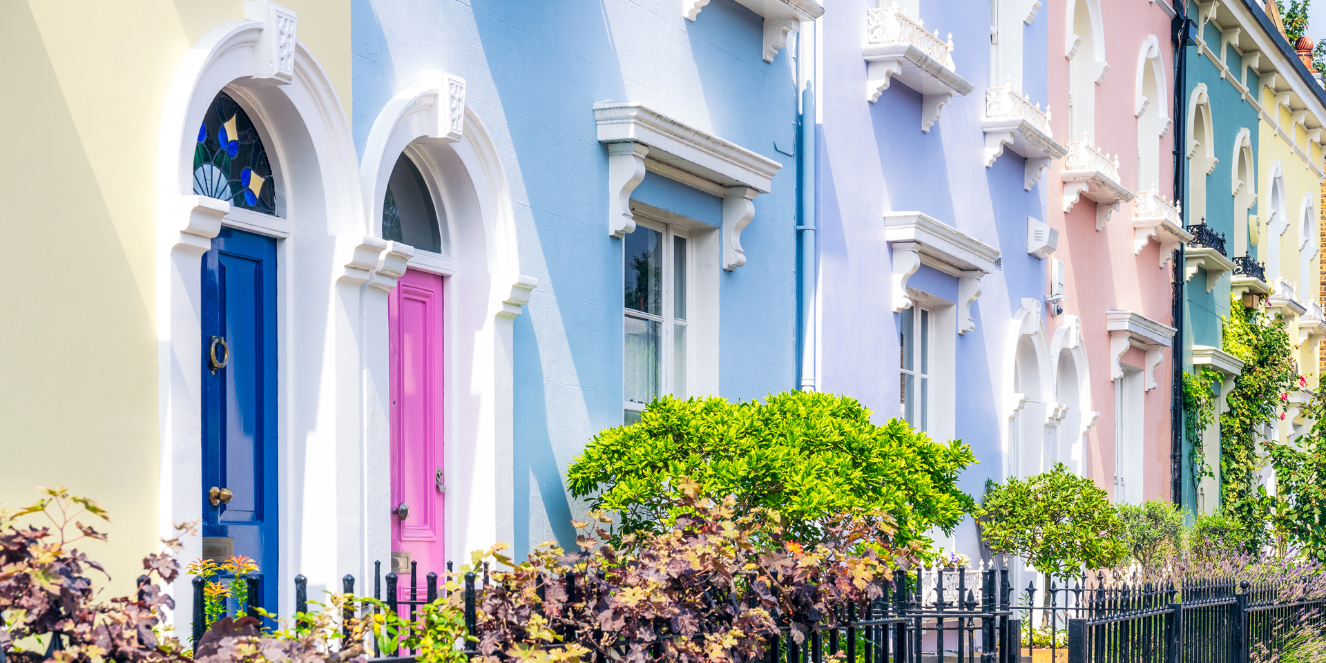 A row of pastel coloured houses on a bright sunny day.