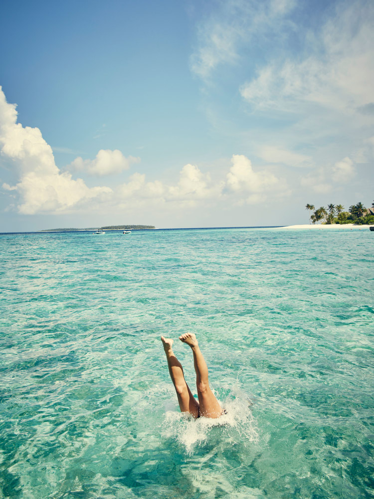 A woman diving into crystal clear water.