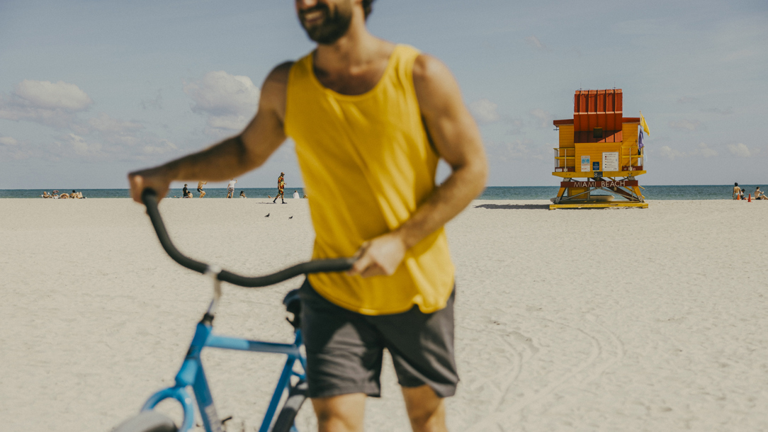 A man with a bike on a beach in Miami.