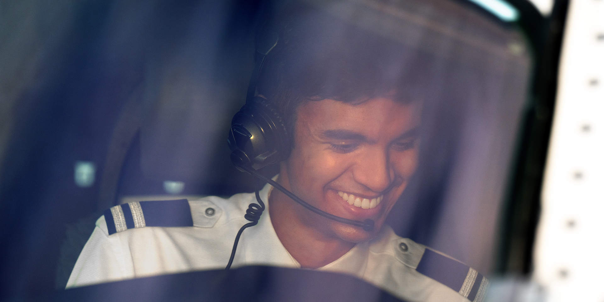 A smiling pilot in the cockpit of a Boeing 787.