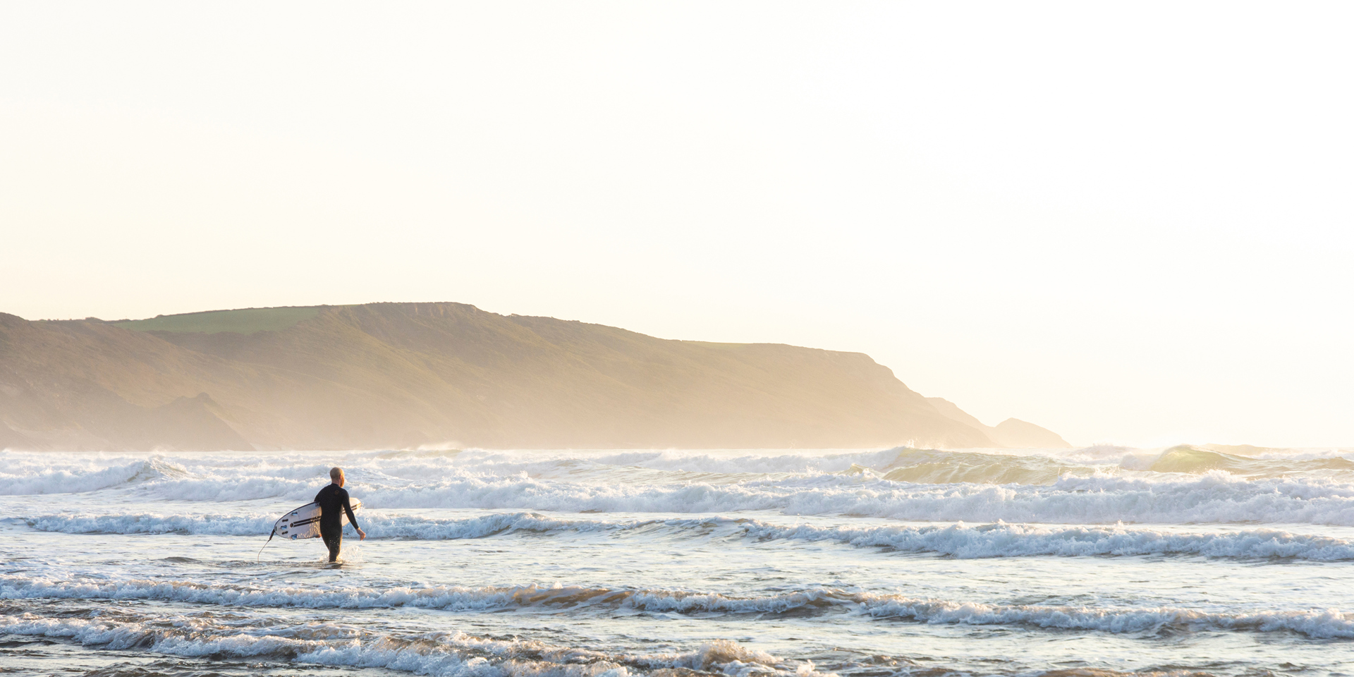 A lone surfer going into the water in Cornwall.