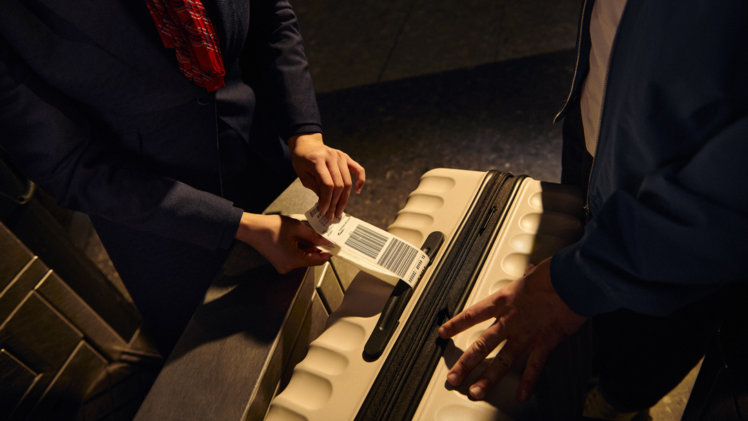 A British Airways staff member putting a tag on a bag.