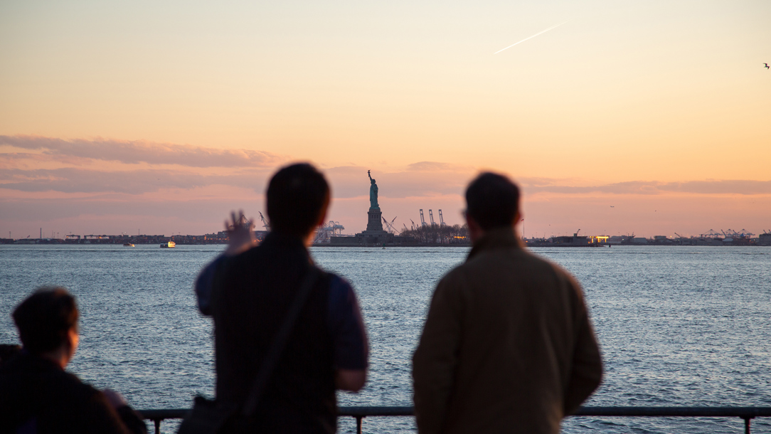 Two men looking at the Statue of Liberty.