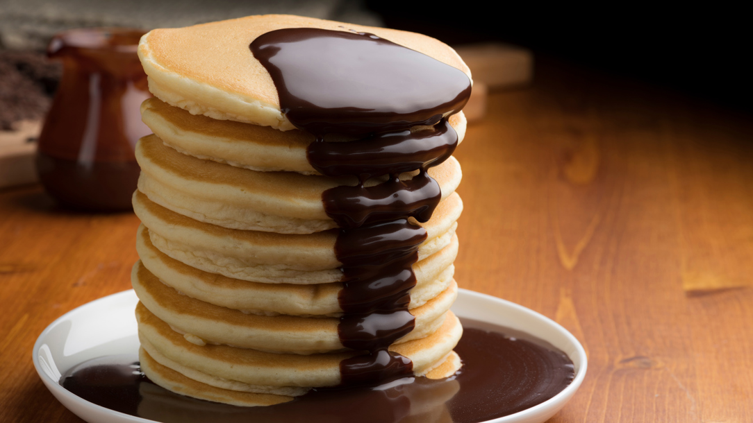 A stack of pancakes with chocolate sauce on them.