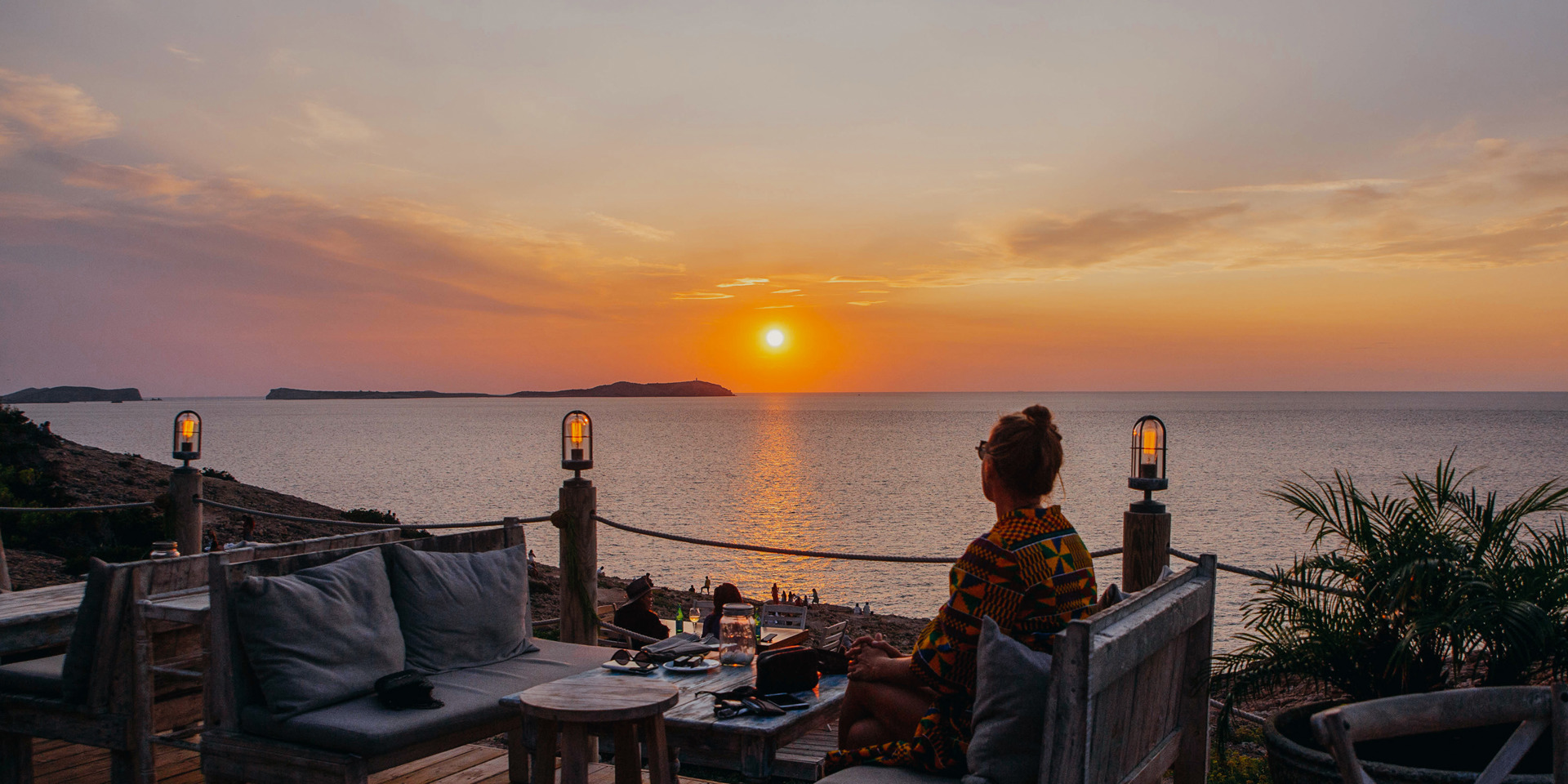 A woman eating alone at sunset.